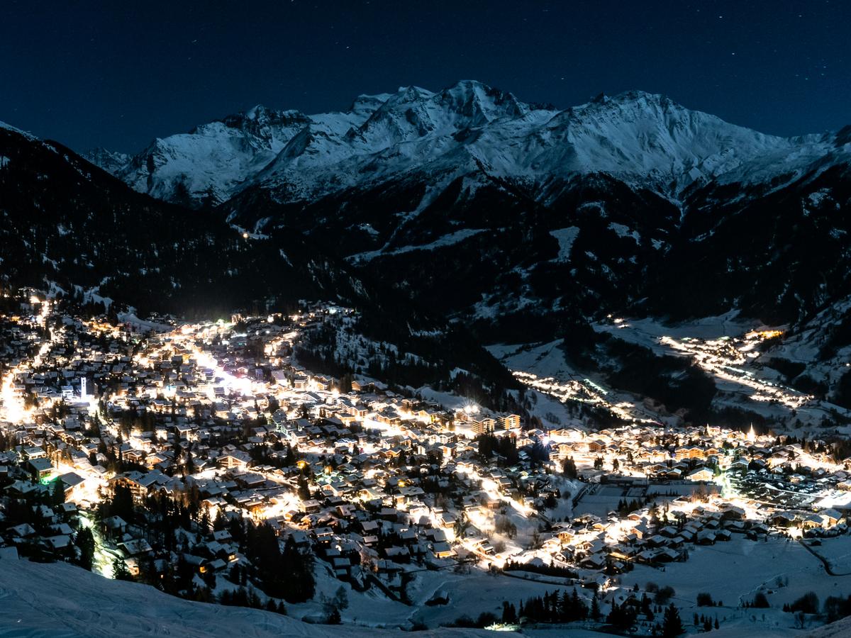 Long exposure of the resort at night with bright white roads winding through the village below dark mountains
